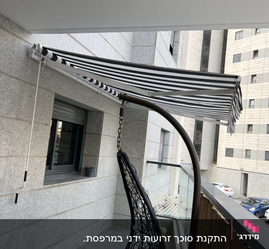 סוכך פסים שחור לבן מותקן על קיר מרפסת